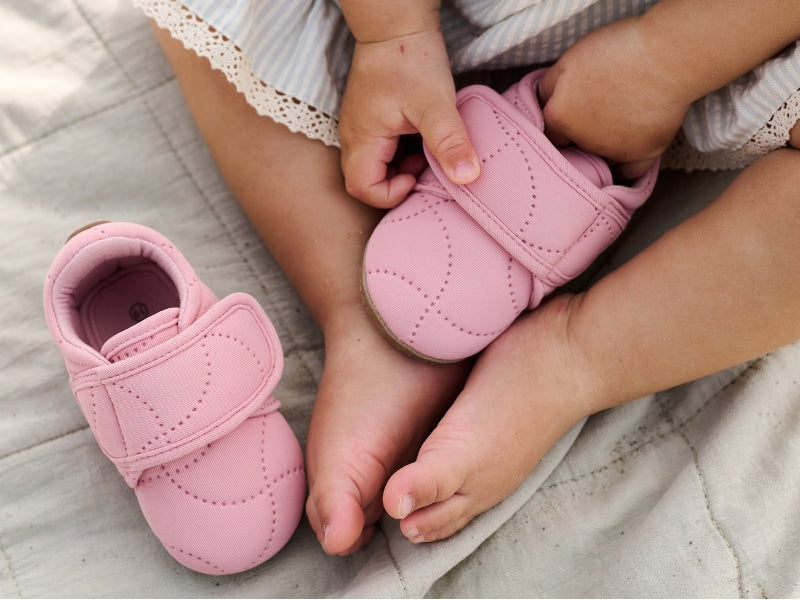 en baby som sitter med et par rosa smokker