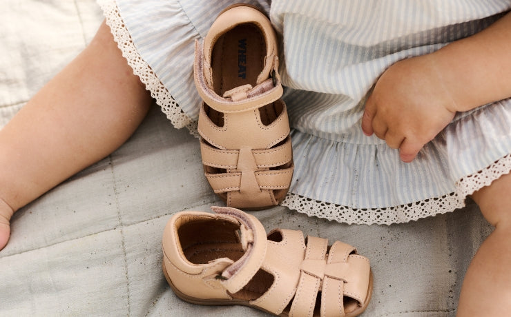 en baby som sitter med et par rosa sandaler